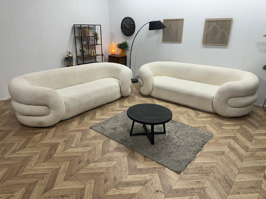 Twee witte bouclé designzetels met ronde vormen in de showroom